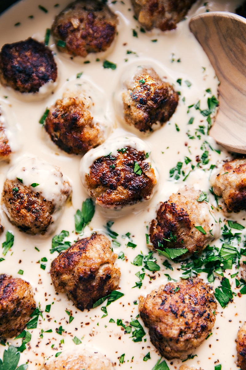 View of Swedish meatballs being stirred into the creamy sauce.