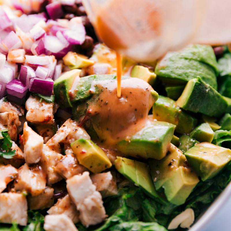 Close-up view of the chipotle-lime vinaigrette being poured over the salad.