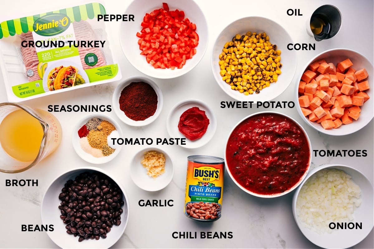 Ingredients In Turkey Chili Recipe All the ingredients prepped and ready for easy assembly, including ground turkey, broth, beans, seasonings, garlic, tomato paste, bell pepper, chili beans, sweet potato, tomatoes, onion, corn, and oil.