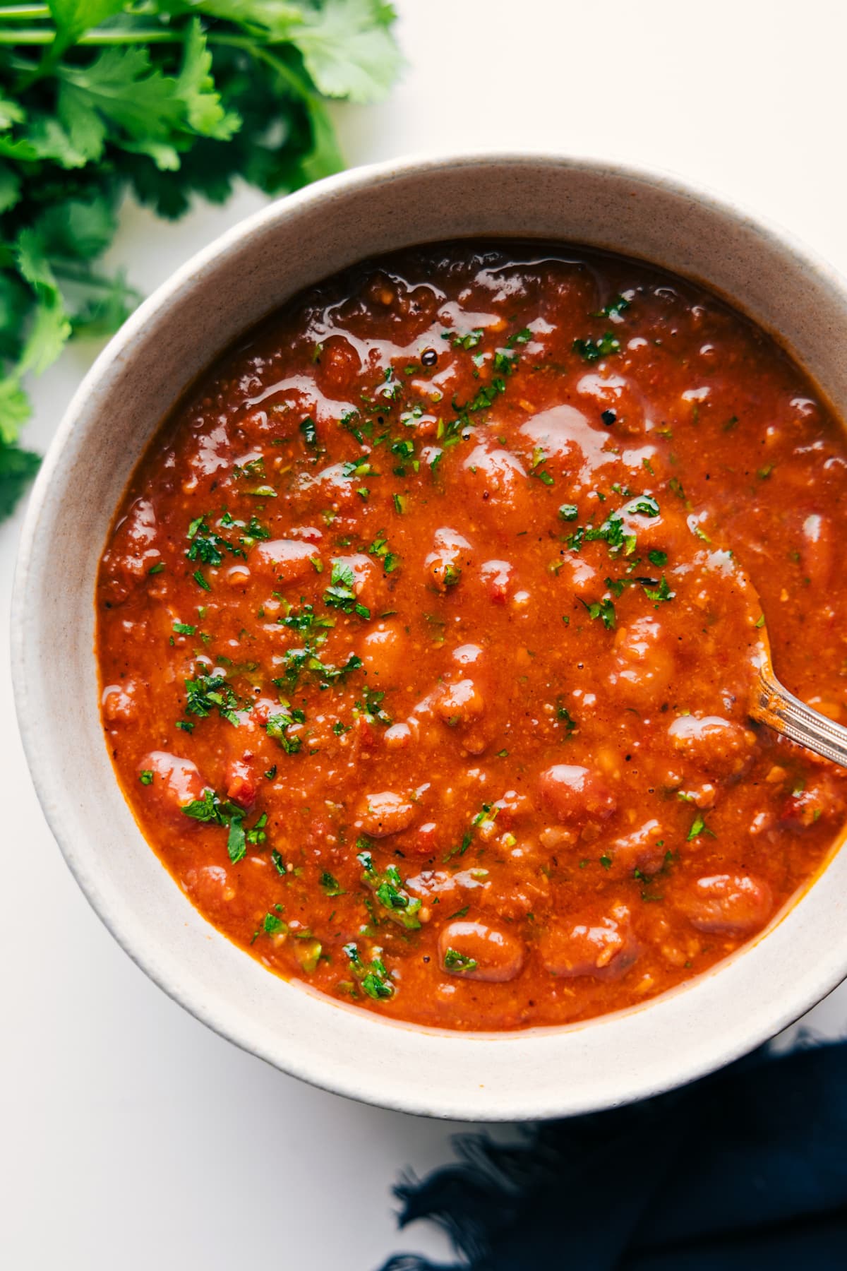 You won't believe how simple these from-scratch Pinto Beans are -- no soaking required! These beans are deeply savory with a smoky flavor and have the best creamy texture! Recipe via ChelseasMessyApron.com #pintos #pintobeans #instantpot #crockpot #slowcooker #nosoak #easy Crockpot pinto beans served in a bowl and topped with fresh cilantro.