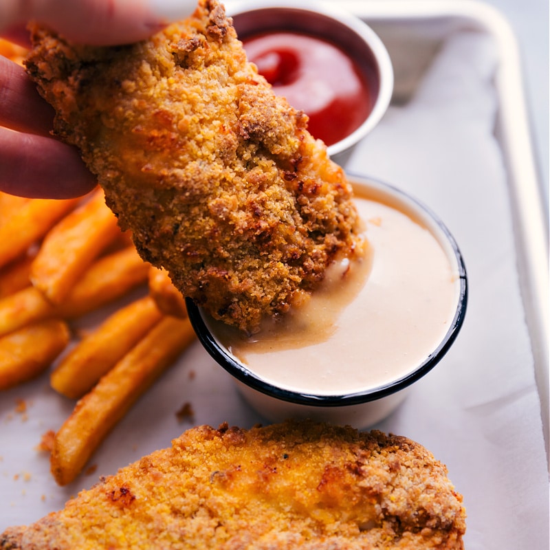 Dipping Air Fryer Chicken Tenders into the sauce.