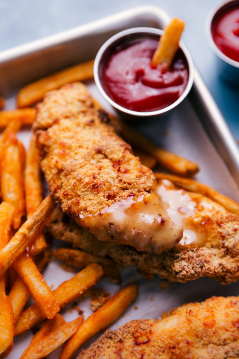Air Fryer Chicken Tenders and fries, on a baking sheet.