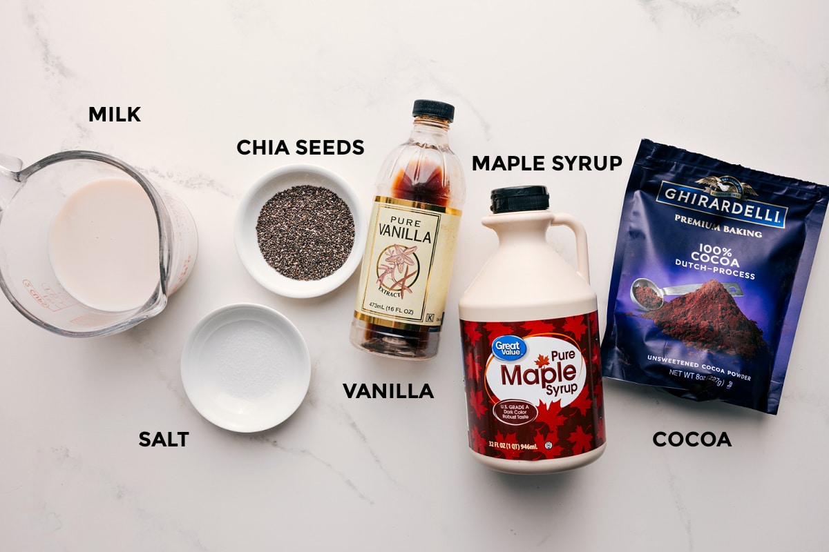 Ingredients In Chocolate Chia Seed Pudding All the ingredients in this recipe prepped out for easy assembly including the milk, salt, chia seeds, vanilla, maple syrup, and cocoa powder.