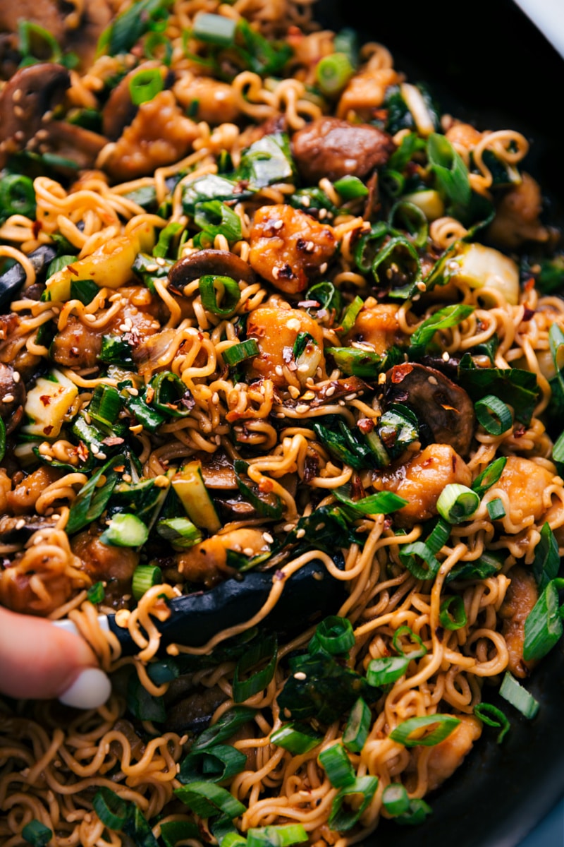 General Tso Ramen in a pot with tongs taking out a bit