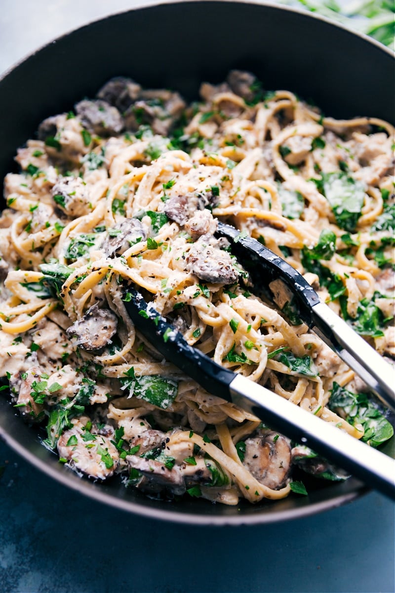 The Best Creamy Chicken Pasta Recipe Creamy chicken pasta in a skillet with a big spoonful being lifted out to serve.