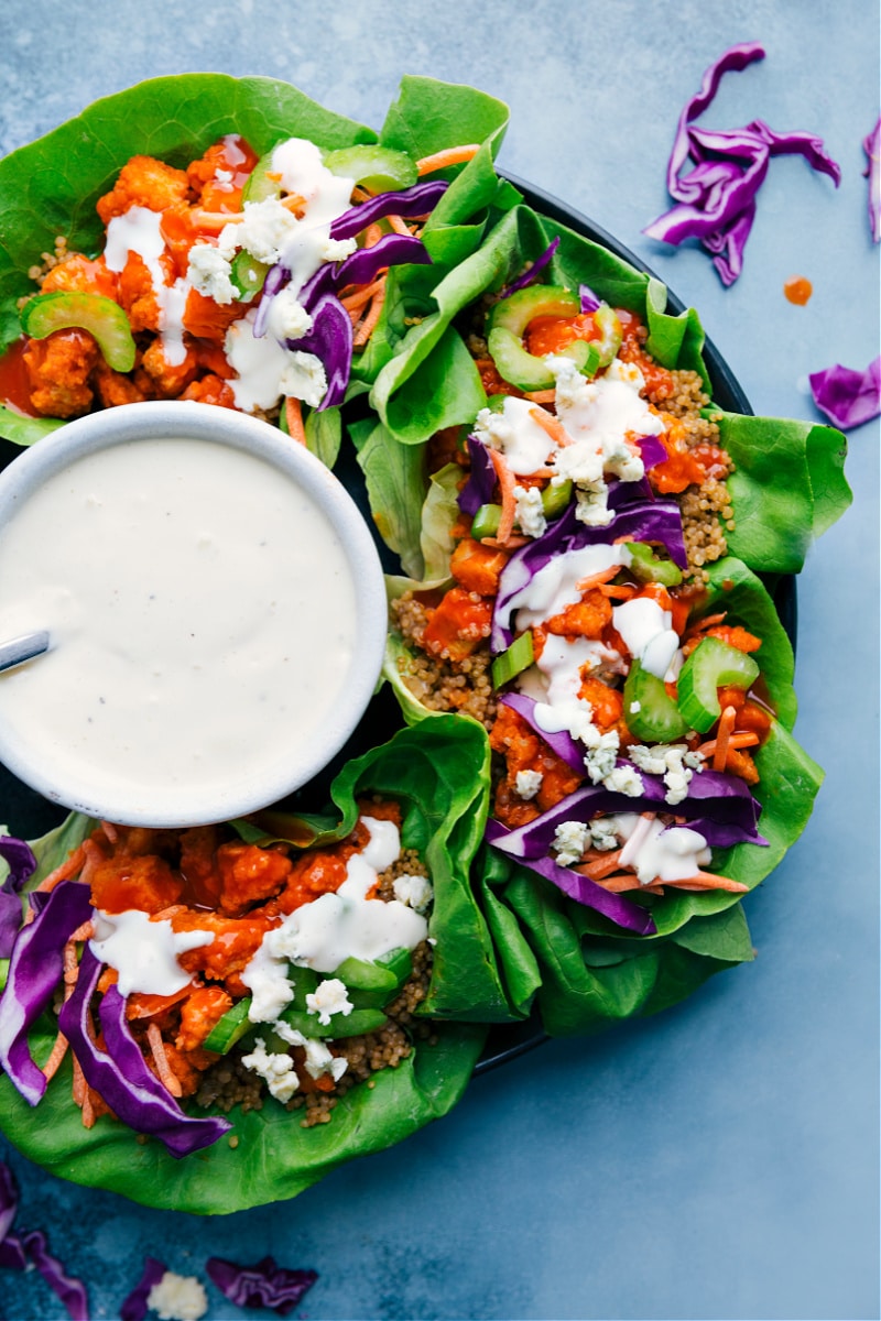 Buffalo Chicken Lettuce Wraps deliver a good hit of heat with a cooling sauce! Crispy chicken is tossed in zesty buffalo sauce and loaded in crispy lettuce wraps, topped with crunchy veggies, and drizzled in a bold bleu cheese (or ranch!) dressing. Recipe via ChelseasMessyApron #dinner #quick #easy #simple #spicy #sauce #quinoa #buffalo #chicken #lettuce #wraps Overhead image of the Buffalo Chicken Lettuce Wraps