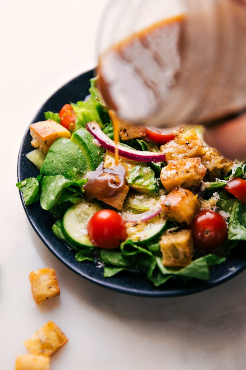 Image of the dressing being poured over a salad