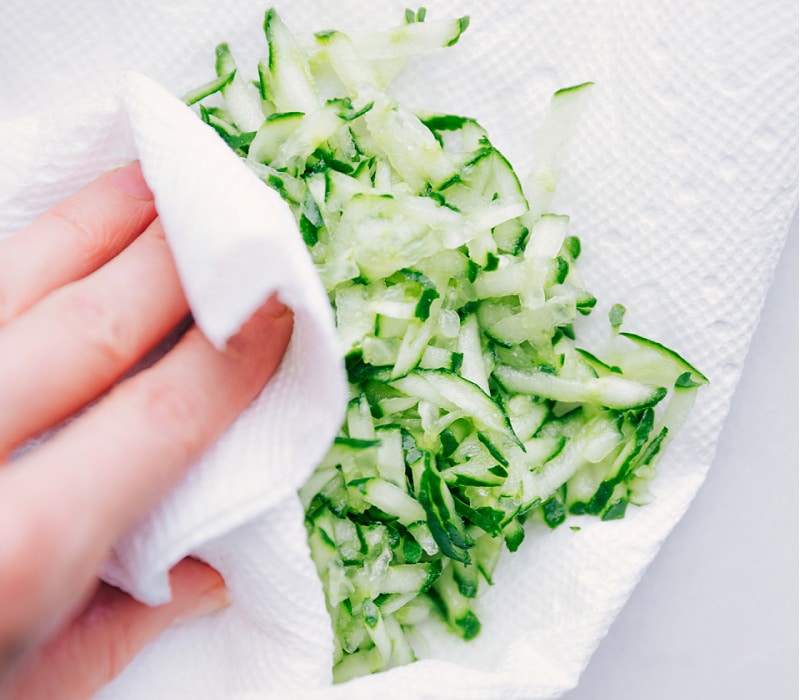 Process shots of tzatziki sauce-- images of the cucumber liquid being blotted with a paper towel.