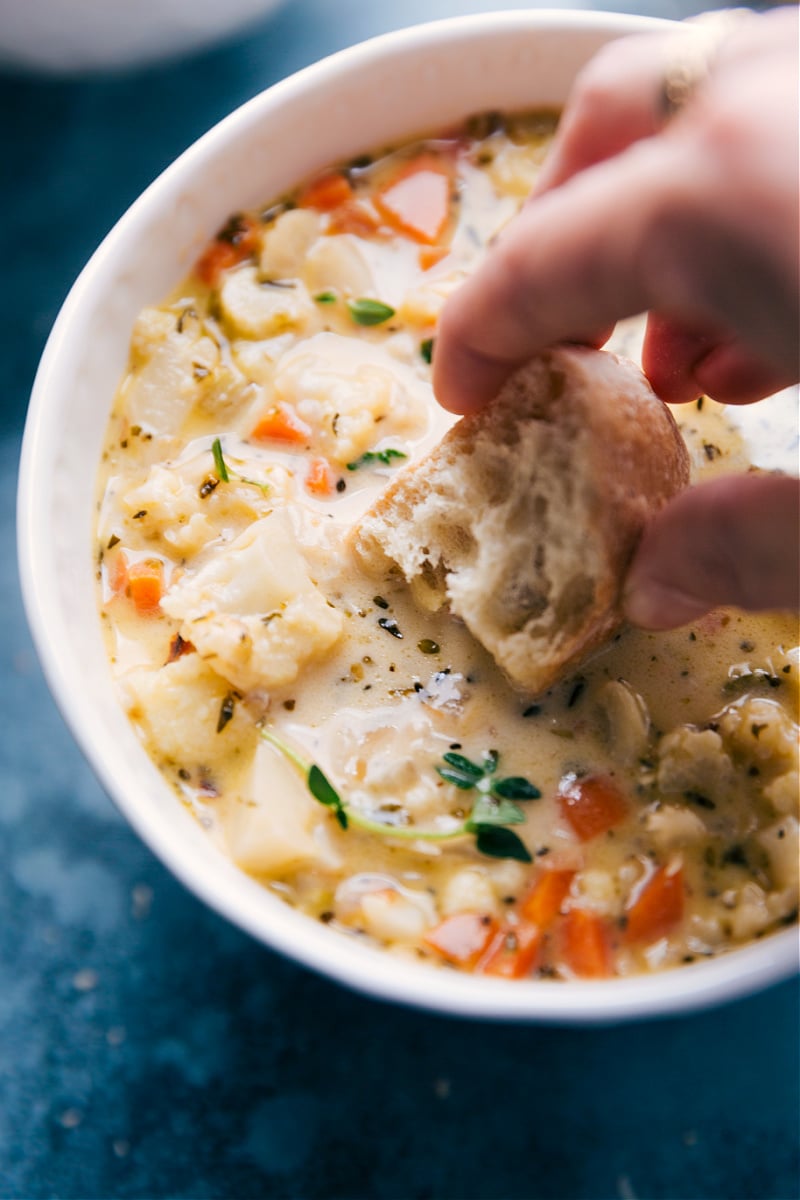 Overhead image of a bowl of Cauliflower Soup in a bowl with bread being dipped in