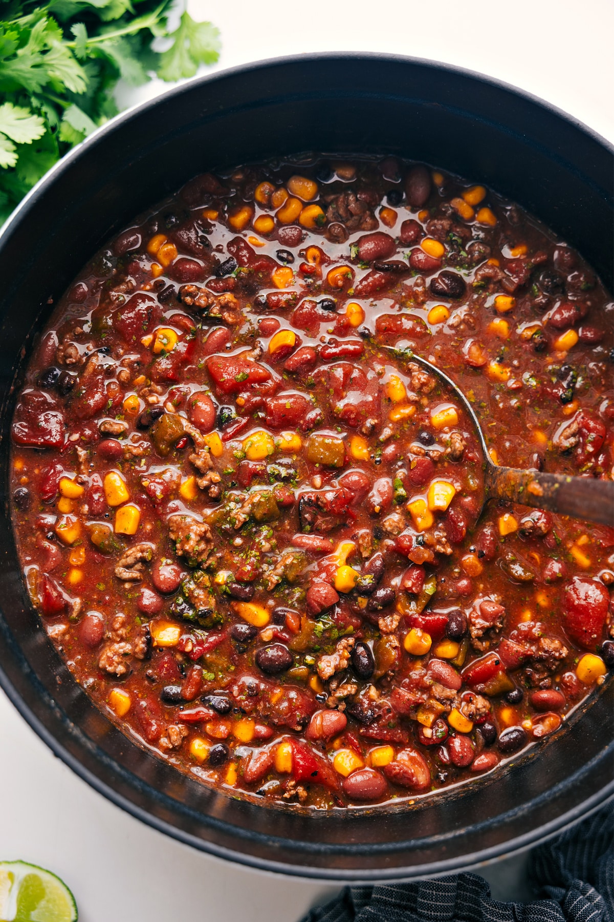 This ridiculously flavorful Taco Chili is better than any restaurant version and is so simple to make -- just empty a bunch of cans in a pot and simmer until you're ready to eat! Load each bowl with your favorite toppings like Cheddar cheese, sour cream, tortilla strips (or chips), fresh lime, and/or cilantro! This chili can be made on the stovetop, pressure cooker, or slow cooker. Recipe via ChelseasMessyApron #dinner #quick #easy #simple #best #corn #beans #healthy #clean #cleaneating #protein #familyfriendly #taco #chili Freshly cooked Taco Chili in a pot, ready to serve.