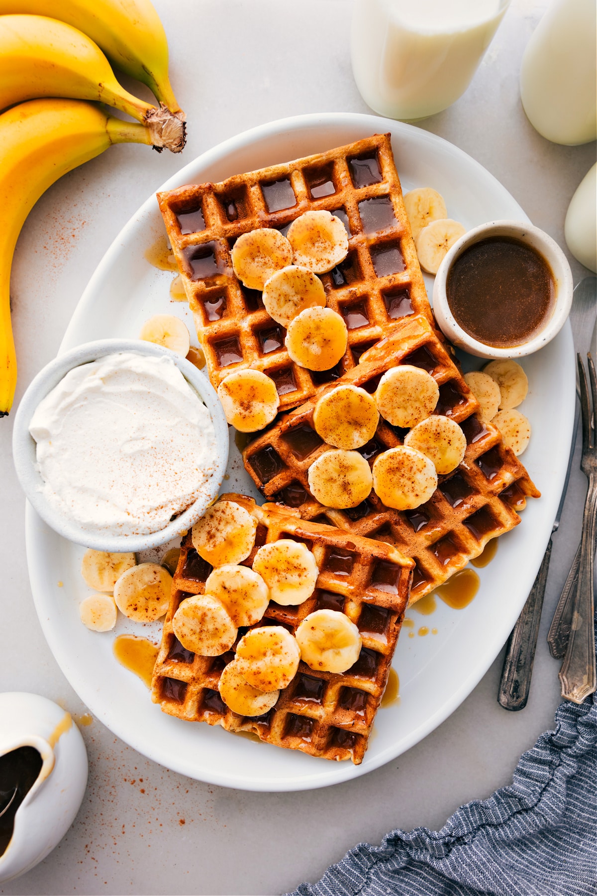Banana Waffles on a platter with syrup drizzled over them.