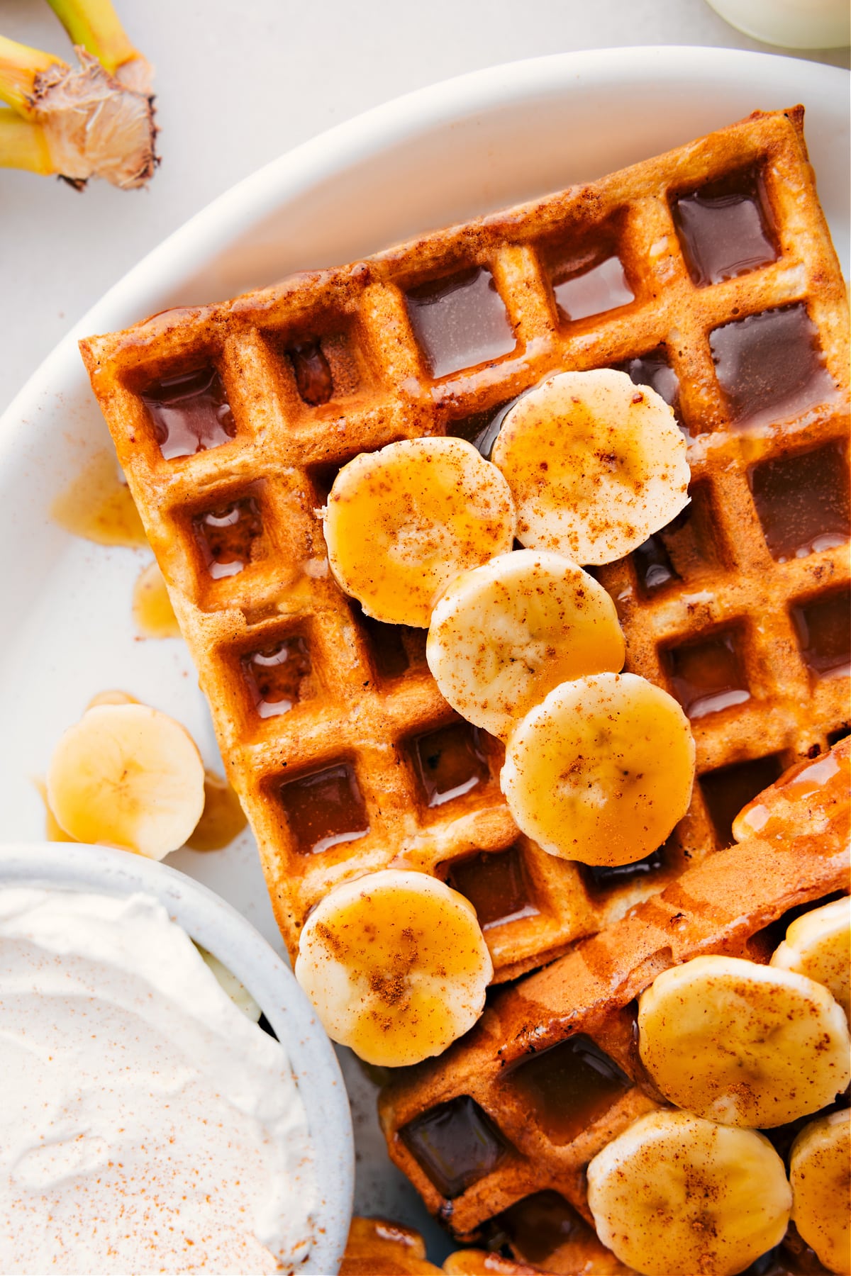 Banana Waffles with syrup and fresh bananas and whipped cream.