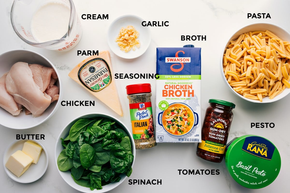 All the ingredients prepped for easy assembly: pasta, pesto, tomatoes, broth, garlic, cream, Parmesan, seasonings, butter, spinach, and chicken.