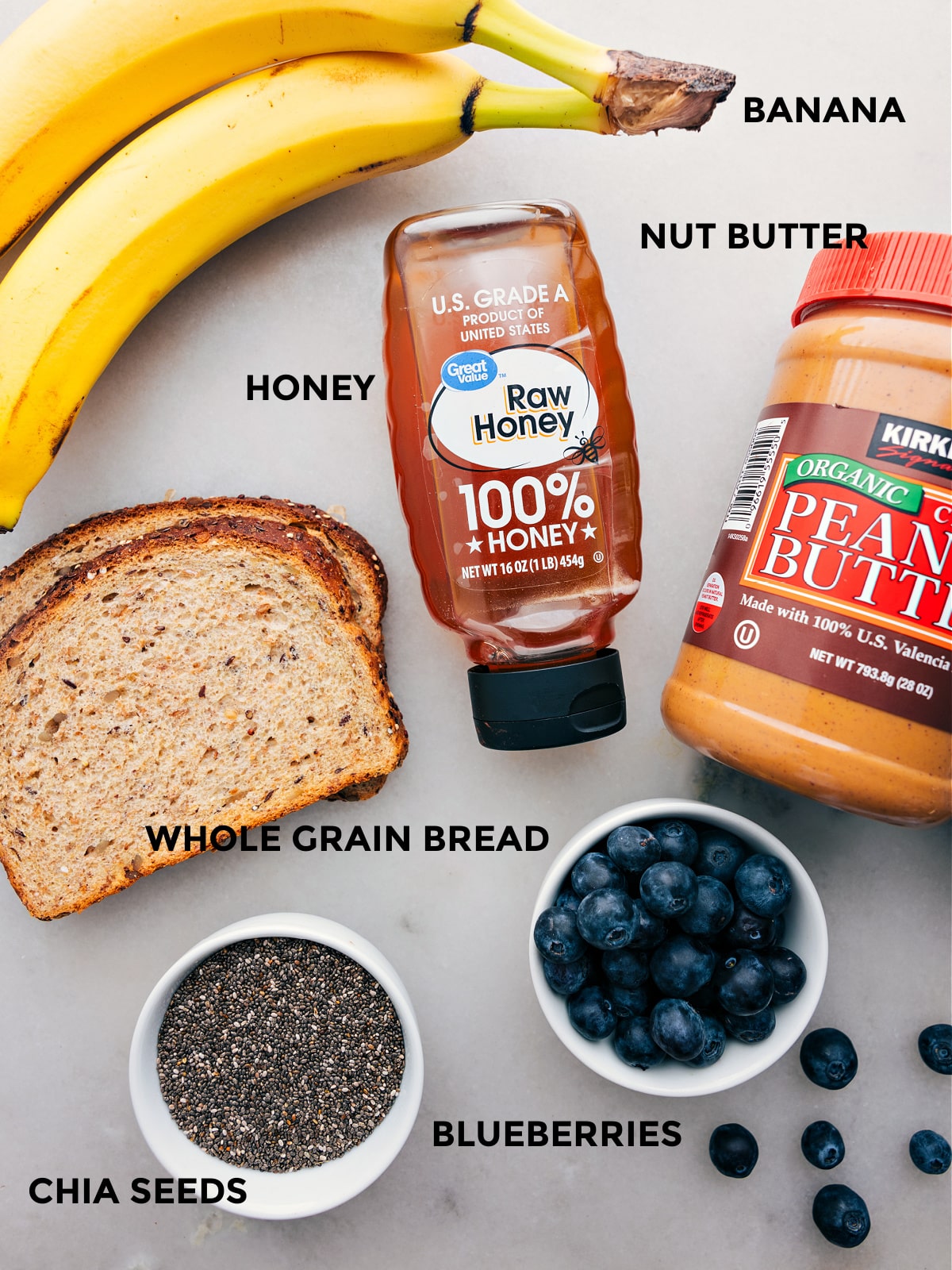 All the ingredients like banana, nut butter, honey, whole grain bread, blueberries, and chia seeds prepped out for easy assembly.