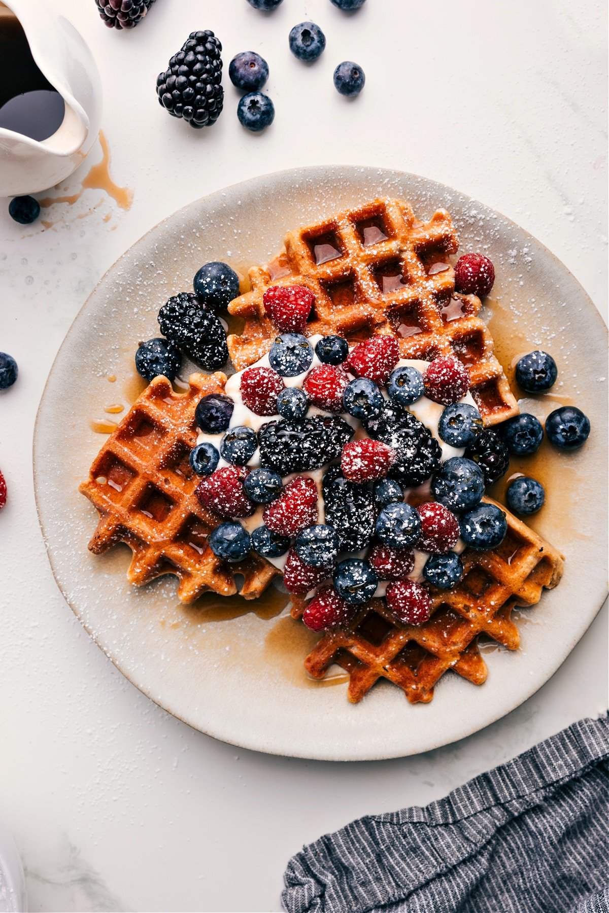 The Best Healthy Waffle Recipe Healthy Waffle Recipe served with syrup, whipped cream, fresh berries, and powdered sugar.