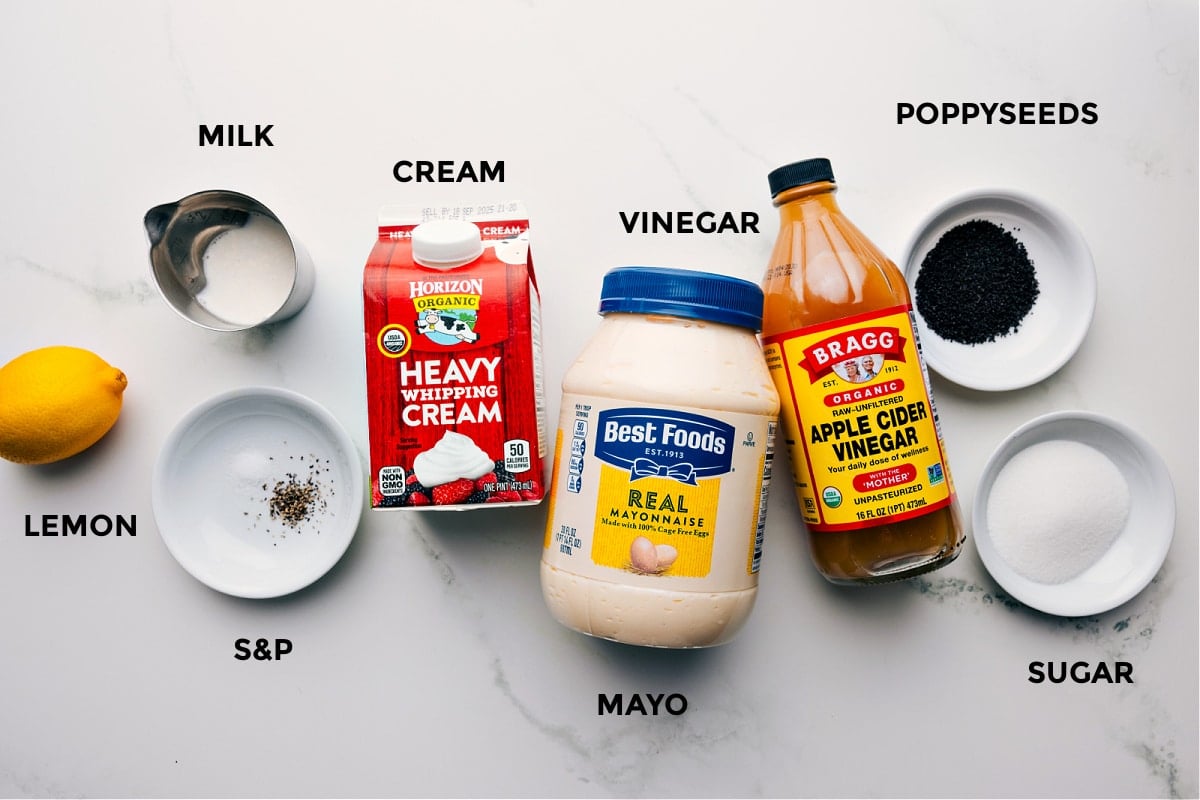 All the ingredients in this recipe prepped out for easy assembly including the lemon, milk, cream, seasonings, cream, vinegar, poppyseeds, and sugar.