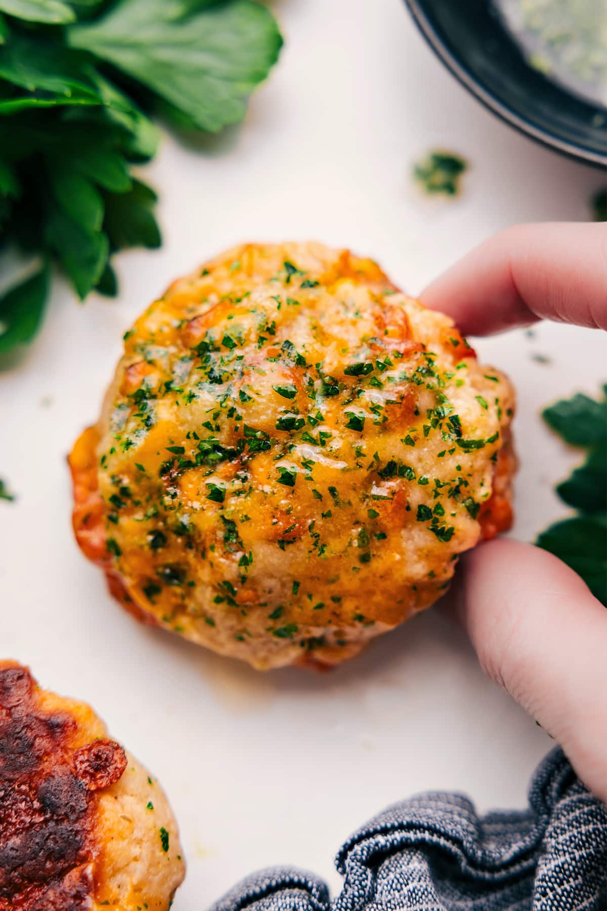 Red Lobster Biscuits are a copycat of the famous drop biscuits sold at Red Lobster restaurant! These biscuits are famous for good reason -- they're fluffy, cheesy, and slathered in the most delicious garlic butter. With this copycat recipe, you can have hot and cheesy biscuits ready in a flash, in the comfort of your own home! Recipe via ChelseasMessyApron.com #biscuits #cheesybiscuits #cheesy #redlobstercopycat #garlicbuttter Red Lobster Cheddar Bay Biscuits fresh from the oven, topped with melted butter and fresh herbs.