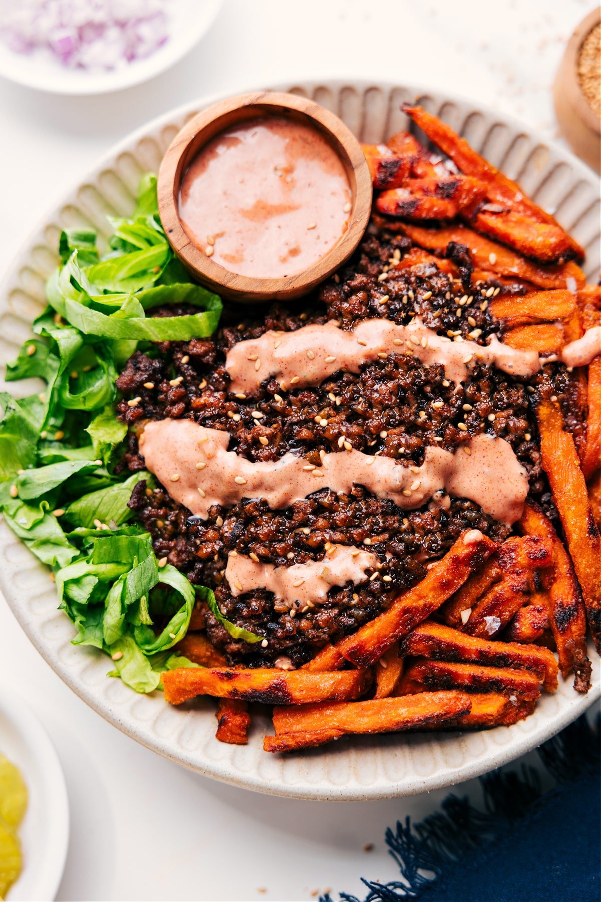 Burger Bowl Or Big Mac In A Bowl Is A Yummy Low-Carb Dinner Burger Bowl with lettuce and sweet potato fries, topped with ground beef, burger sauce, and a sprinkle of sesame seeds.