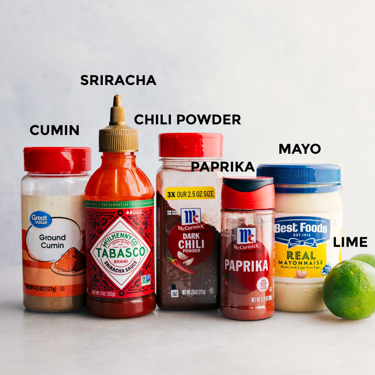 All the dressing ingredients including cumin, sriracha, chili powder, paprika, mayo, and limes prepped out for easy assembly.