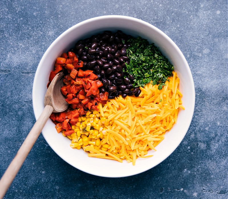 Ingredient shot: a bowl with roasted red peppers, black beans, corn, Cheddar and cilantro.