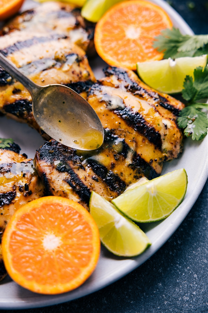 View of citrus sauce being drizzled over cooked chicken thighs