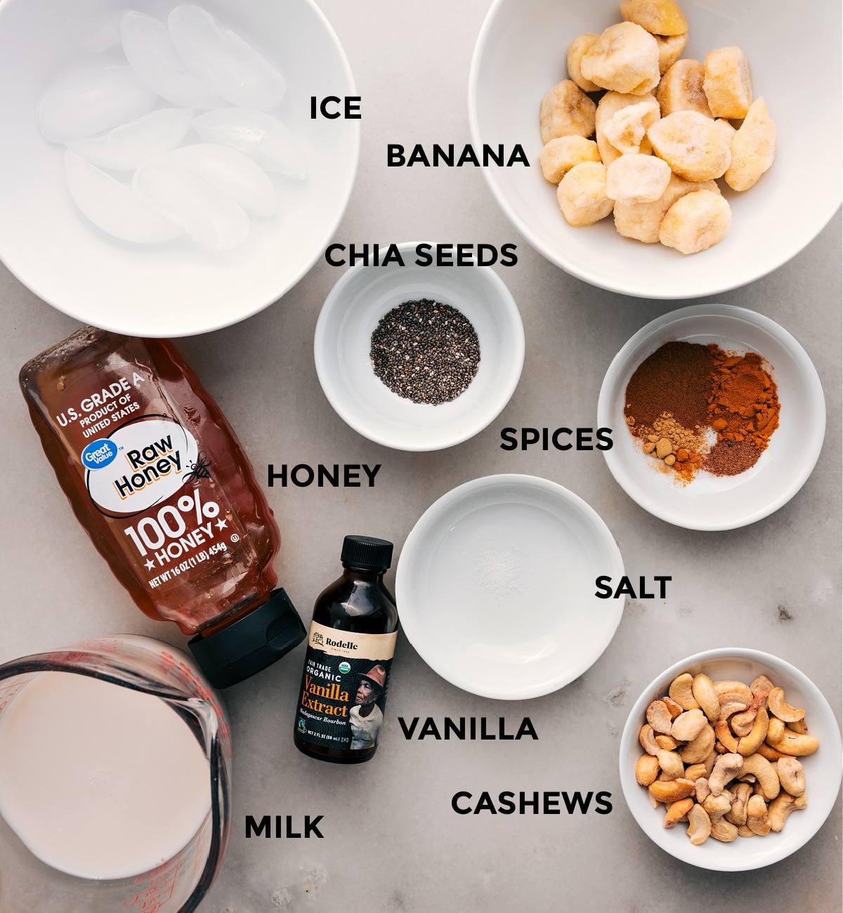 Ingredients for this recipe, prepped for easy assembly: bananas, ice, spices, honey, chia, salt, vanilla, cashews, and milk.
