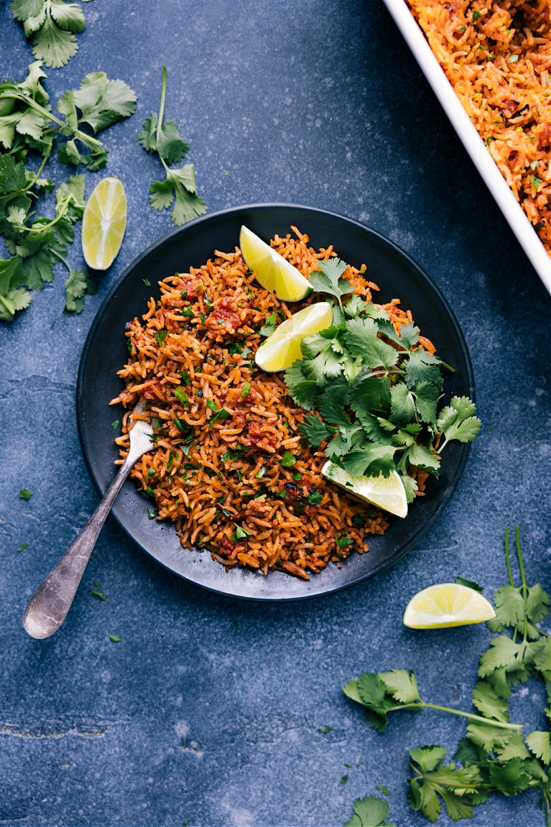 Overhead view of Mexican Rice on a plate, with lemon wedges and cilantro.