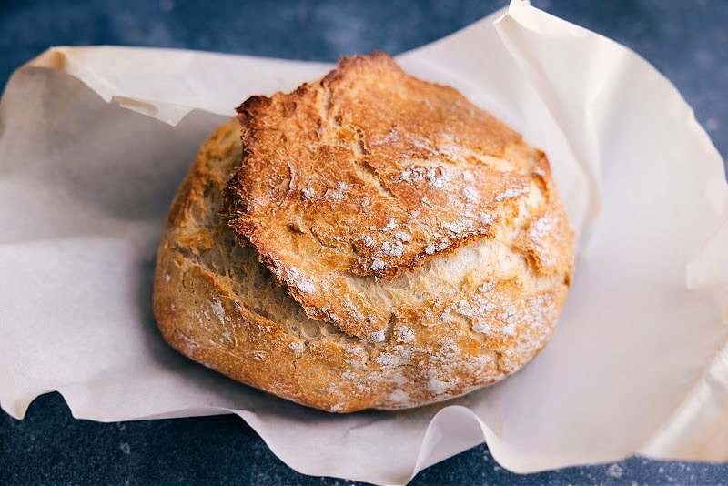 A loaf of No-Knead Bread on a sheet of parchment paper