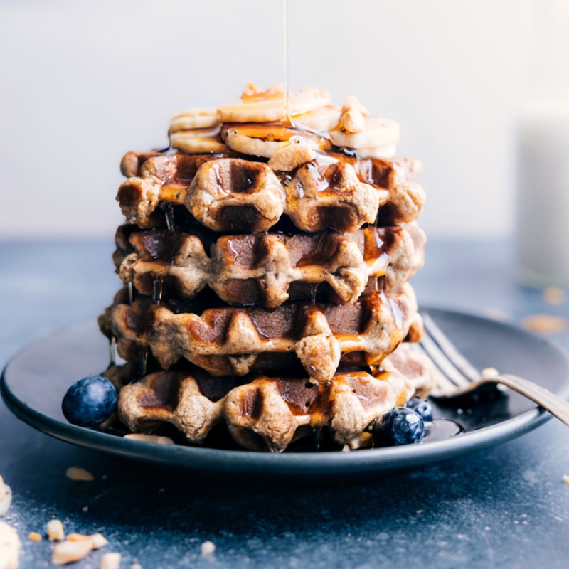 Image of a stack of Banana Waffles on a plate with syrup being drizzled on top
