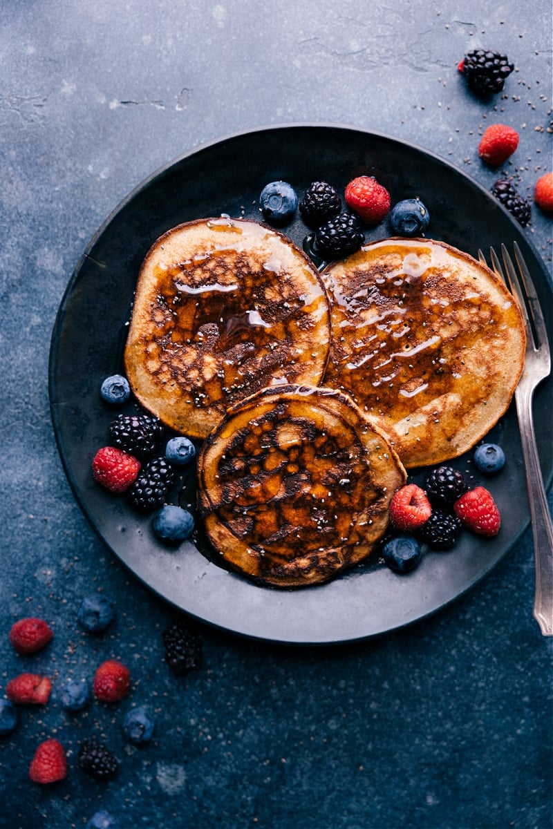 Far out shot of three Healthy Pancakes with maple syrup and berries. Fork about to dig in!