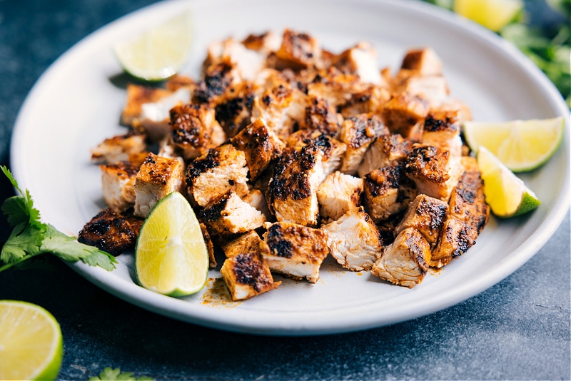 Image of a plateful of grilled chicken with lime wedges on the side