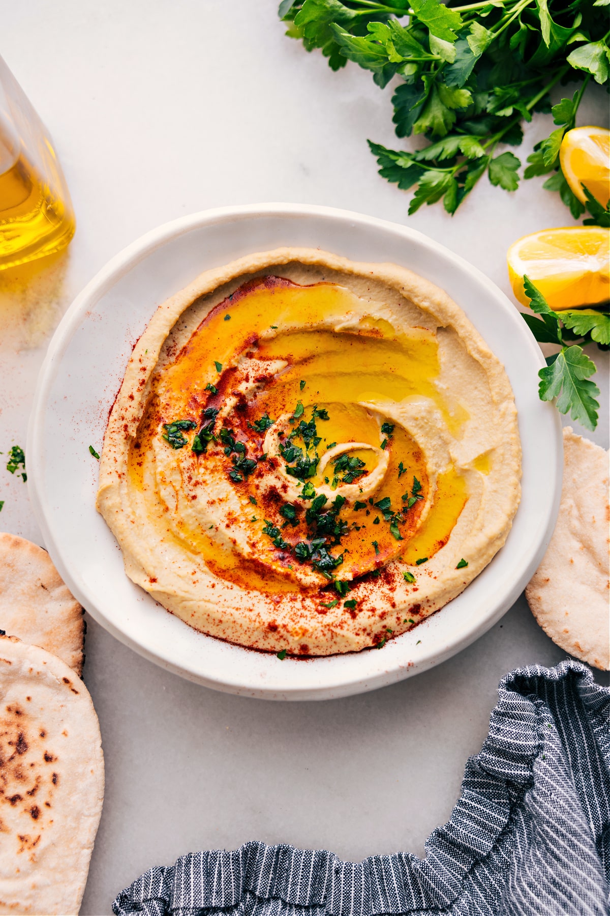 The Best Hummus Recipe Hummus recipe in a bowl topped with extra olive oil, paprika, and parsley.