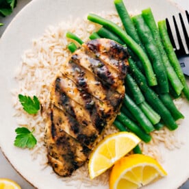 Italian Chicken Marinade recipe on a plate over a bed of rice with green beans.