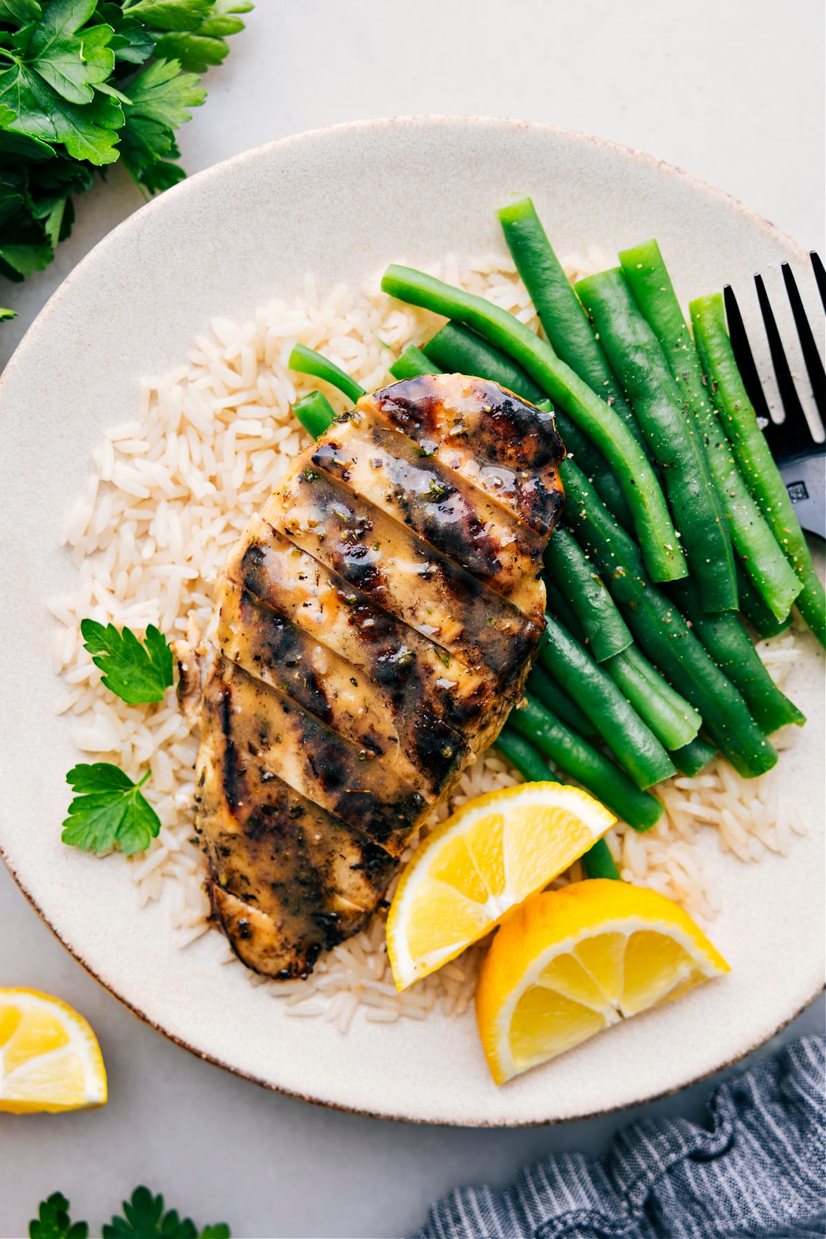 Italian Chicken Marinade recipe on a plate over a bed of rice with green beans.