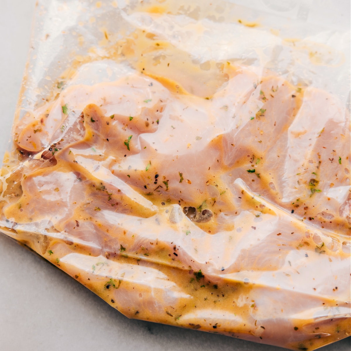 The meat marinating in the dressing in a freezer size bag.