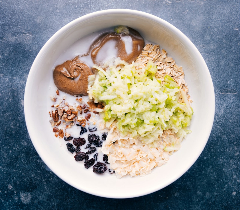 Process shots of Bircher Muesli- image of the apple and milk being added to the bowl