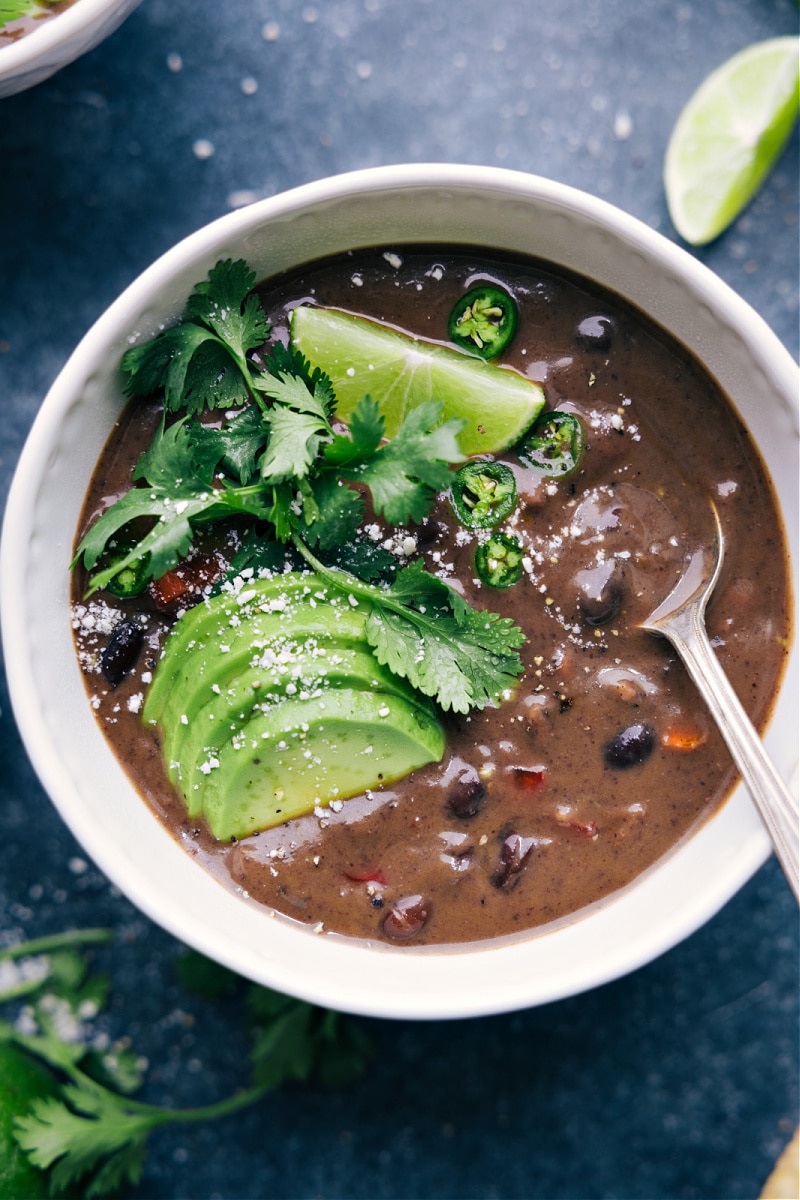 View of Black Bean Soup served with lime, avocado and cilantro