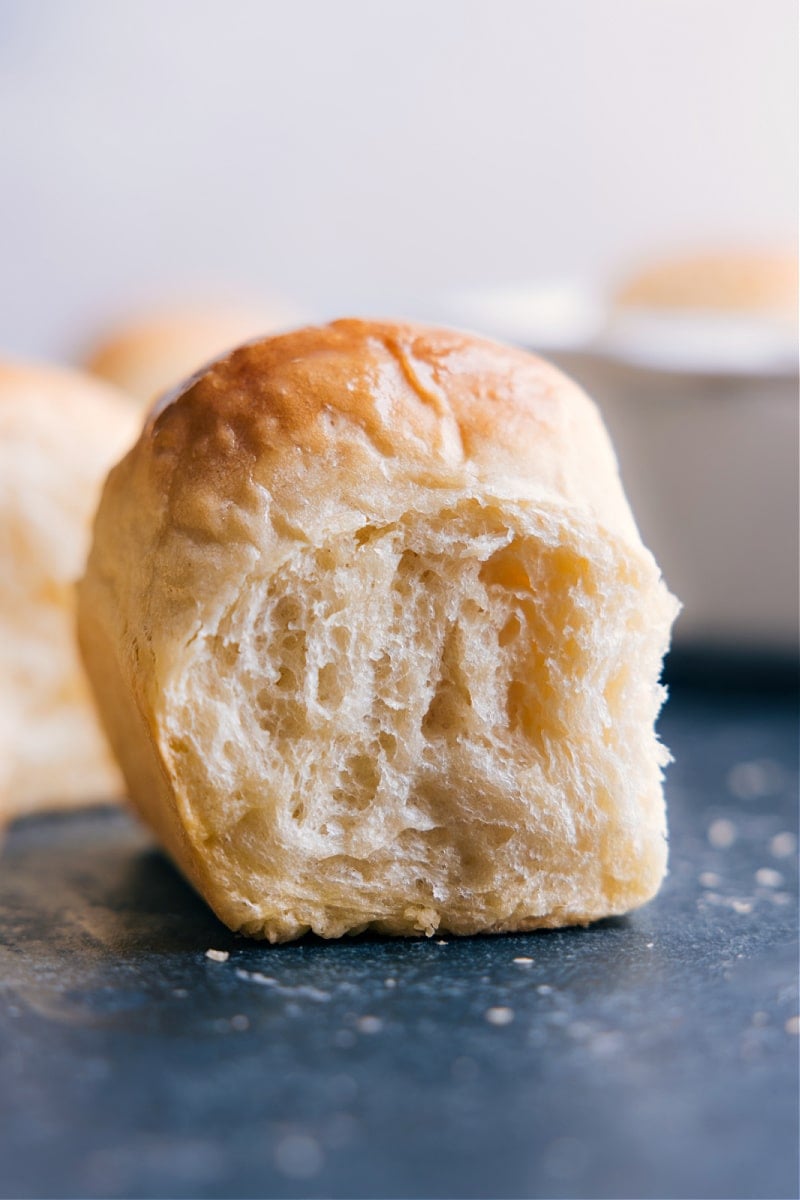 Our favorite Dinner Rolls are made easy with NO stand mixer, no hand mixers, and no kneading required! These rolls rise high with big soft centers and perfectly crisp edges. Yes, really, these rolls are life-changing! Recipe via chelseasmessyapron #appetizer #familyfriendly #noknead #thanksgiving #best #easy #simple #kidfriendly #dinner #rolls Image of a Life-Changing No-Knead Dinner Roll, ready to be enjoyed