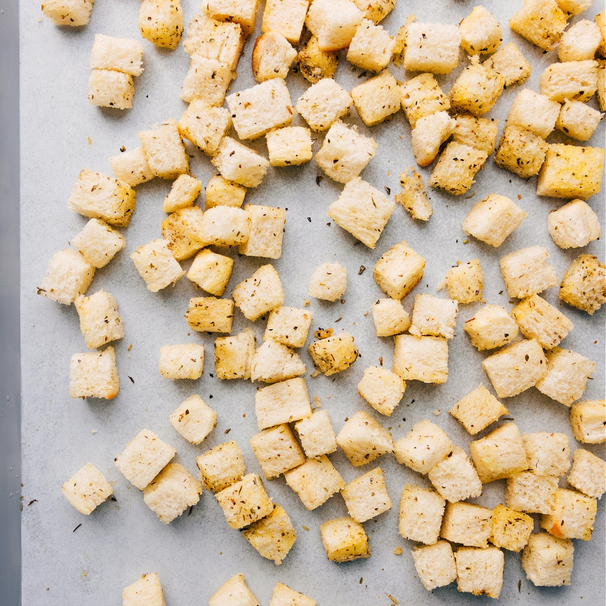 Homemade croutons on a sheet pan, coated in oil and seasonings, ready to be roasted.
