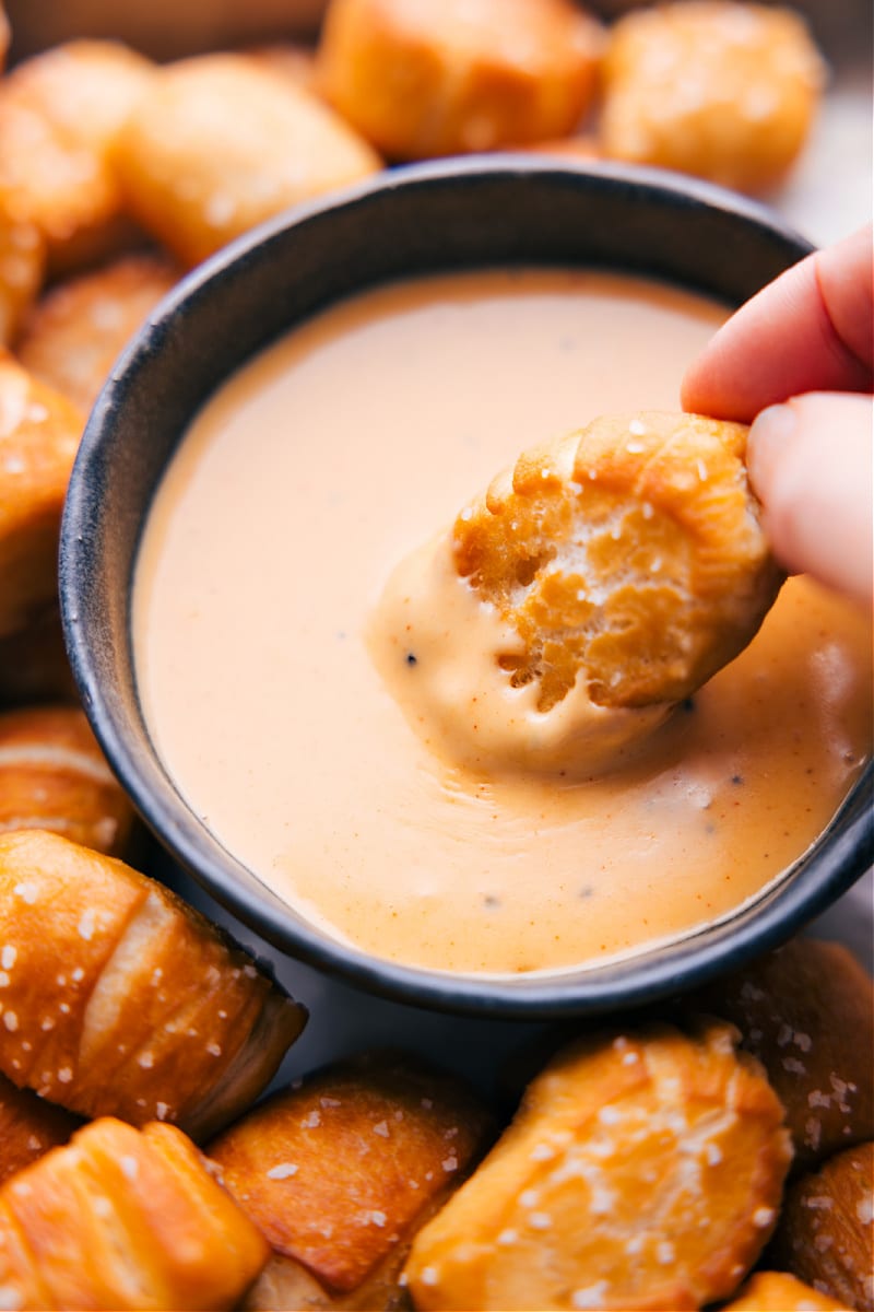 Image of the pretzel bites being dipped in cheese sauce