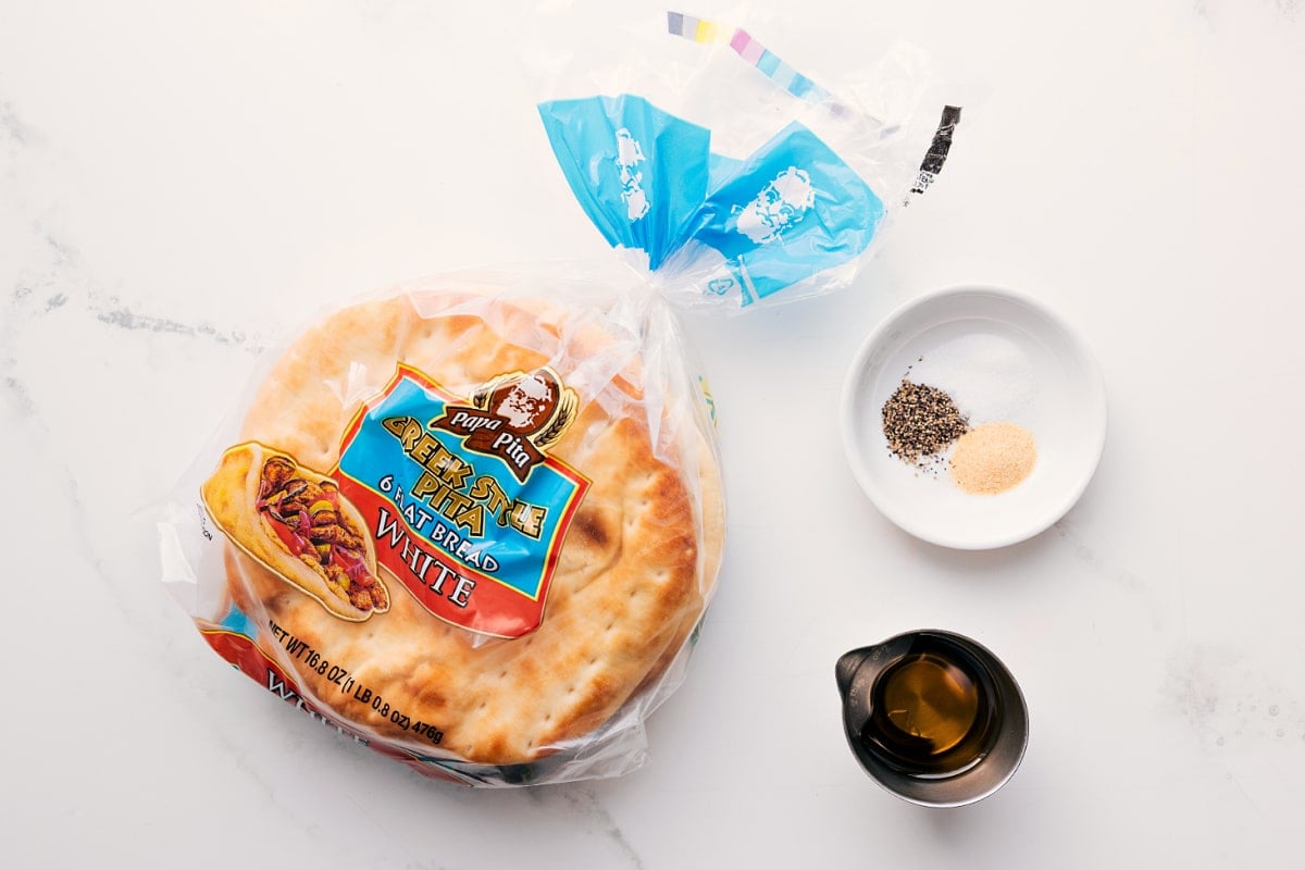 How To Prep The Pita For This Pita Chip Recipe The ingredients in this recipe prepped out for easy assembly including the pita bread, seasonings, and oil.