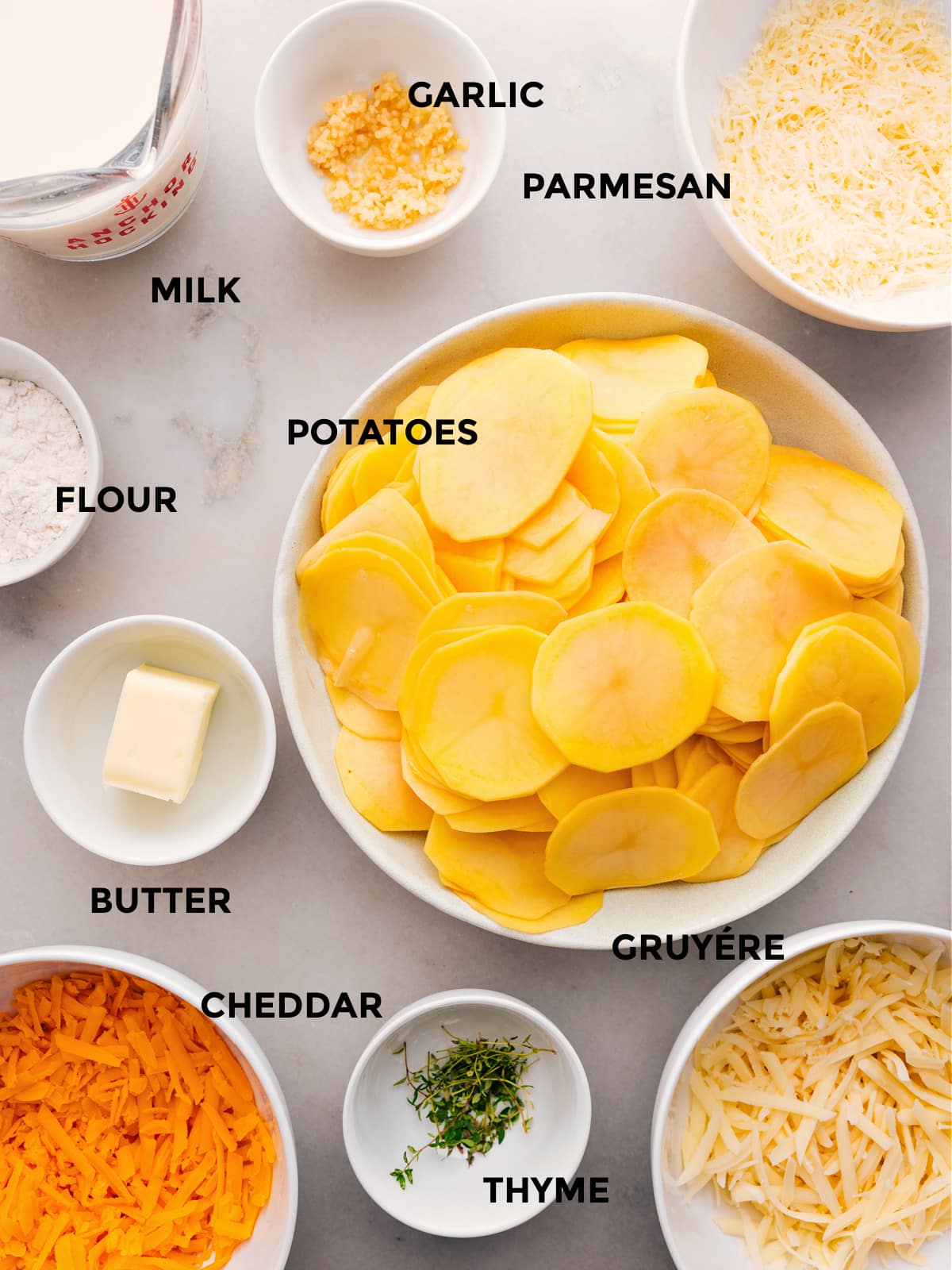 The ingredients for this recipe—potatoes, flour, butter, thyme, cheese, milk, and garlic—are prepped and ready for easy assembly.