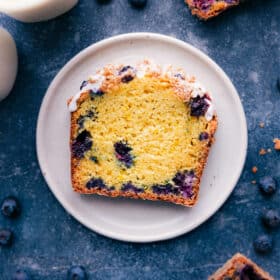 A slice of the finished lemon blueberry bread showing its moist delicious center and topped with a sweet icing.