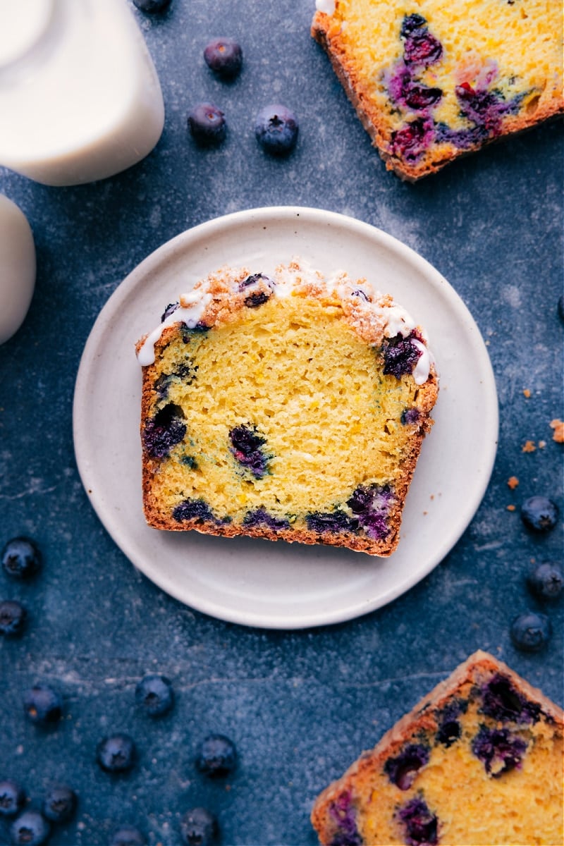 A slice of the finished lemon blueberry bread showing its moist delicious center and topped with a sweet icing.