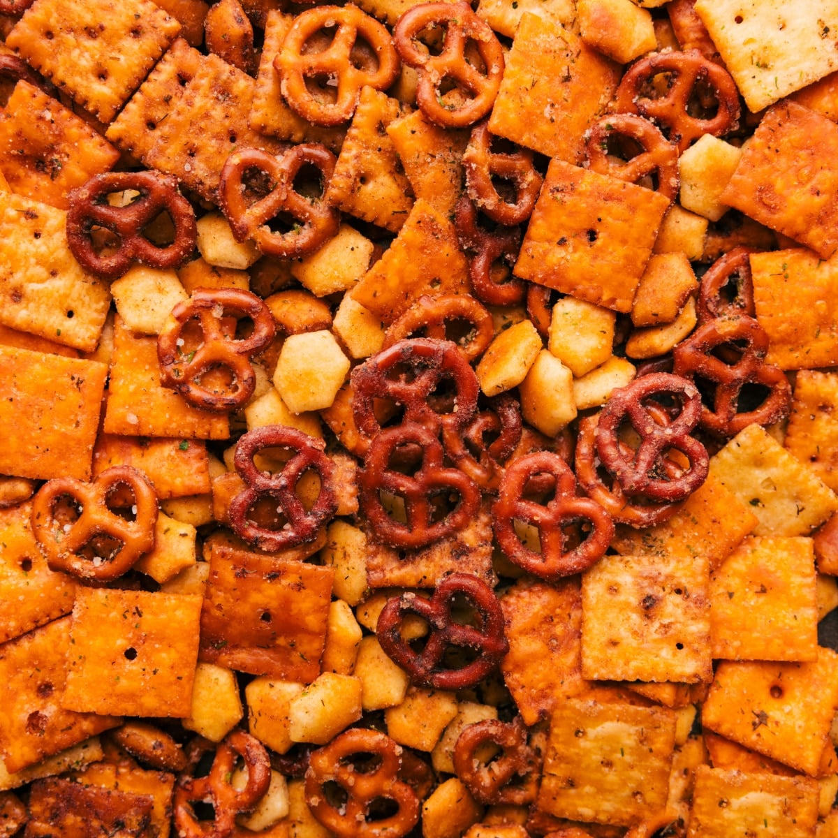 This Chex Mix Recipe is loaded with crispy cereal, pretzels, cheese crackers, and nuts. The seasoned butter pulls everything together into a mix that is nothing short of addicting! Recipe via ChelseasMessyApron.com #snackmix #chexmix #chex #snack #cereal Finished party mix spread on a sheet pan after baking.