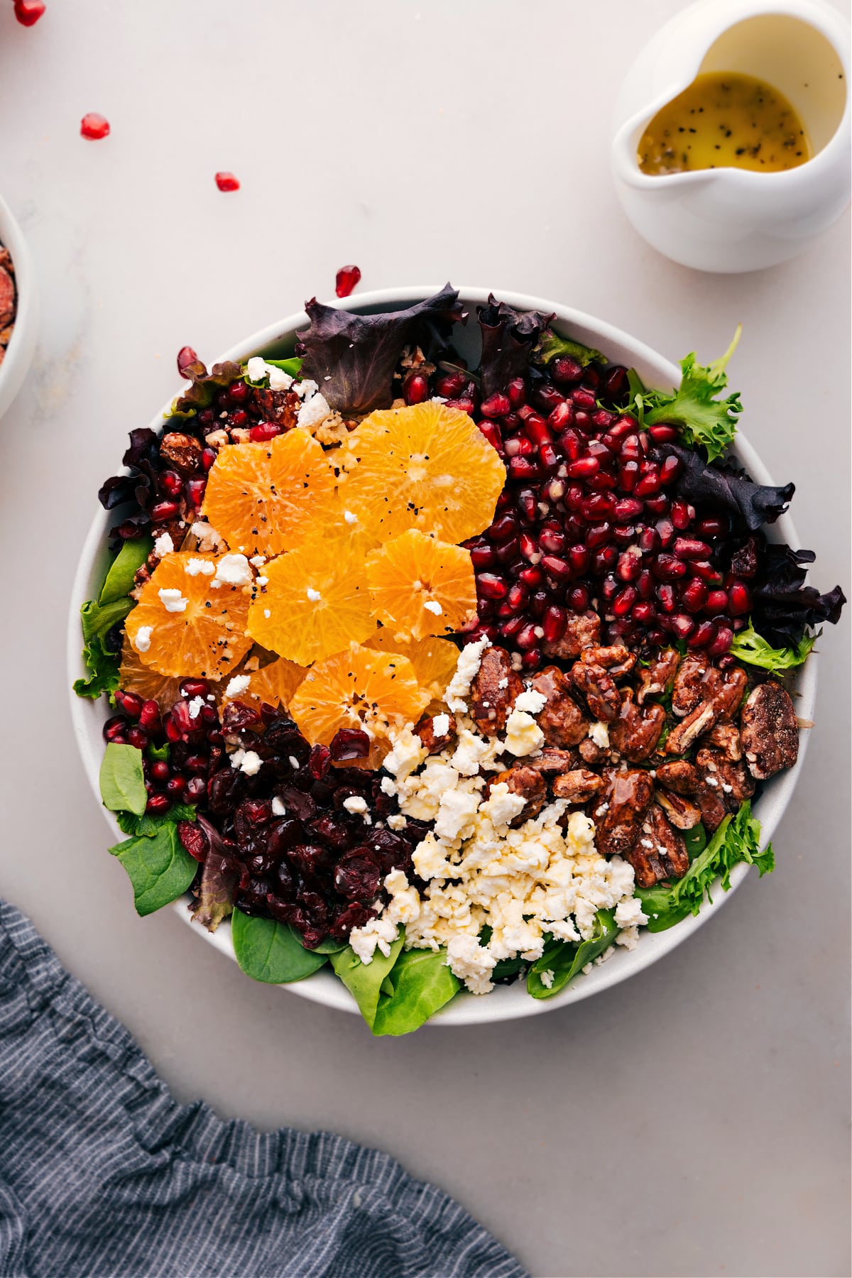The Best Winter Salad Recipe Winter Salad with ingredients tossed together, then topped with oranges, feta, nuts, pomegranates, and dried cranberries.