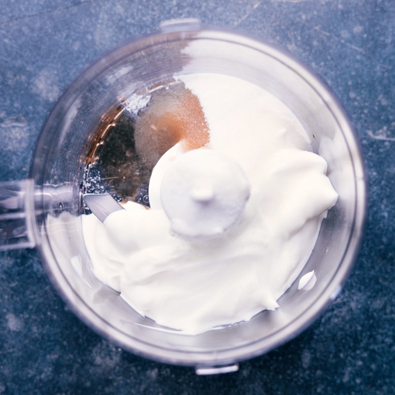 Overhead image of the yogurt, sweetener, salt, and vanilla being added to the food processor