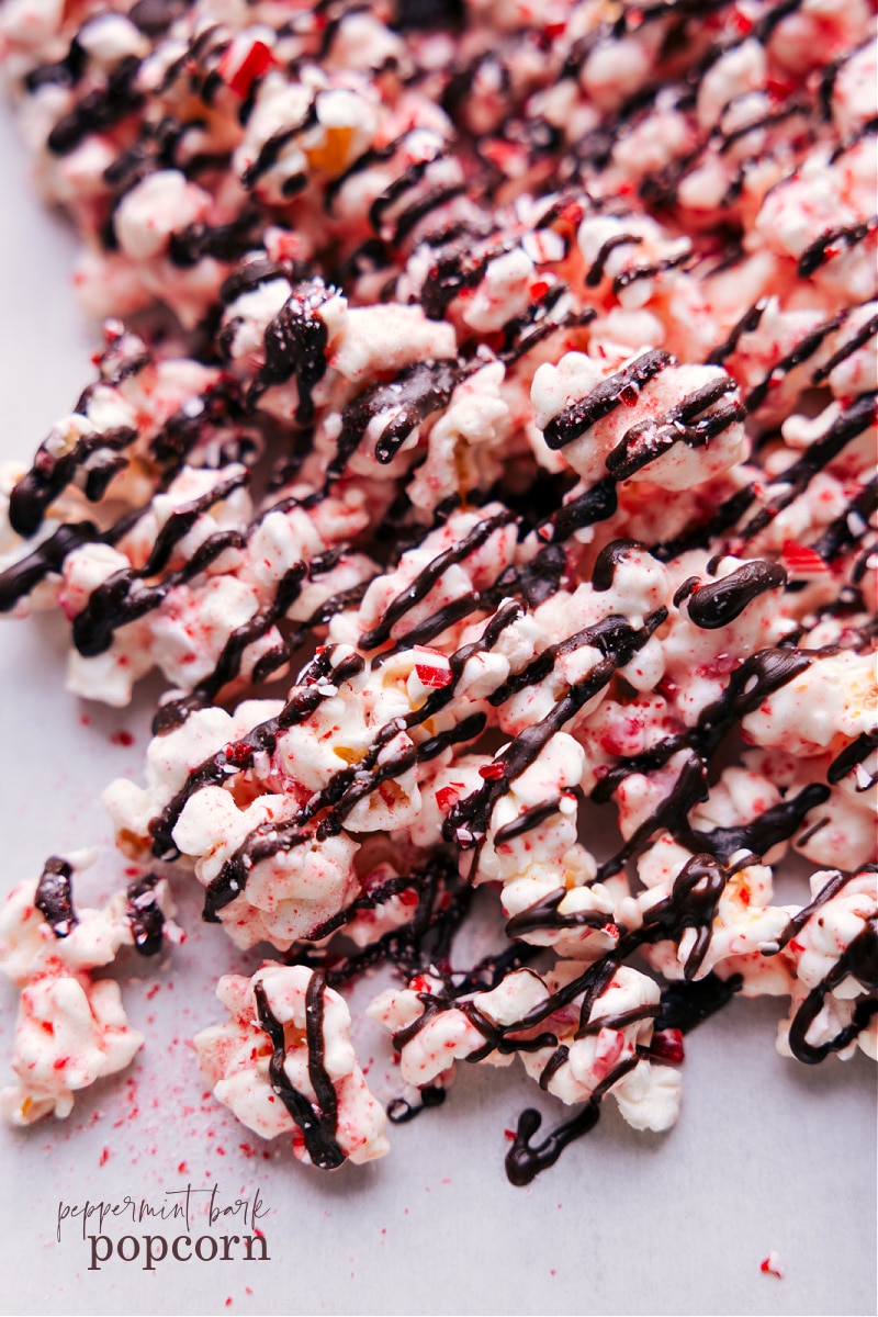 Peppermint Popcorn is a treat you won't want to miss this holiday season! Toss popcorn in white chocolate and crushed peppermint; then finish with a chocolate drizzle. This sweet snack mix is nothing short of addicting! Recipe via chelseasmessyapron #dessert #best #quick #easy #simple #christmas #snackmix #holiday #holidaytreats #chocolate #peppermint #popcorn Overhead image of the snack ready to be enjoyed