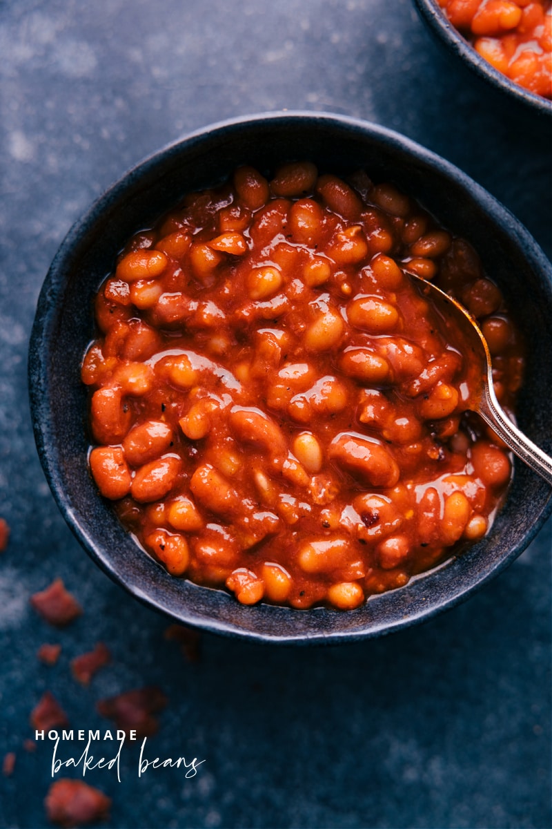 Are you ready for the ultimate summer BBQ or cookout side dish? These Baked Beans are made with a delicious blend of spices, bacon, and onion and are the perfect addition to any summer party. Recipe via ChelseasMessyApron.com #bakedbeans #beans #picnics #summermeals #savory #homemade #bacon Overhead image of a bowl of Baked Beans