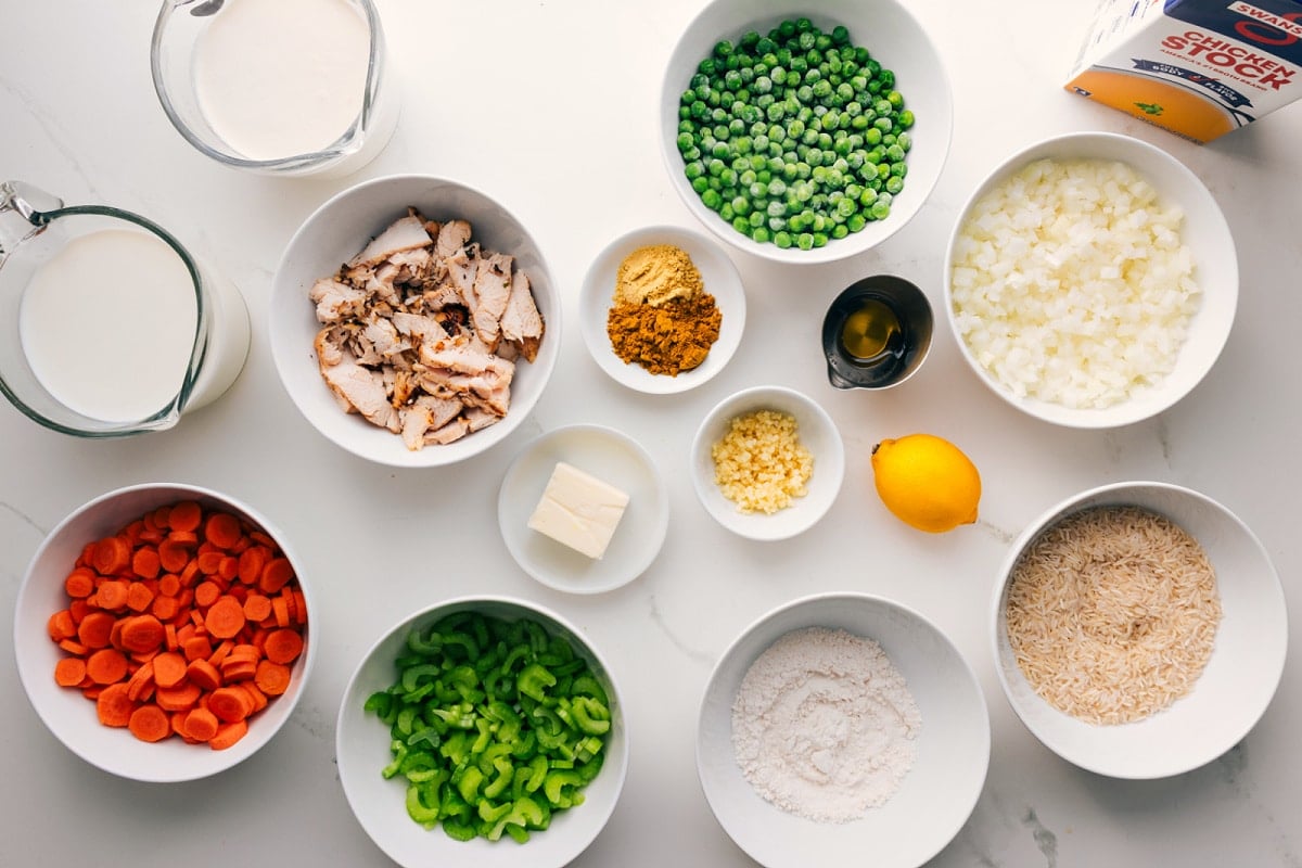 We've got tender shredded chicken, rice, carrots, onion, and celery all simmering together in a rich, creamy, and flavorful base that will have you coming back for seconds (or thirds). Get ready to cozy up with a big bowl of this comforting goodness! Recipe via chelseasmessyapron #dinner #quick #easy #simple #best #familyfriendly #comfortfood #healthy #curry #chicken #rice #soup All the ingredients in this recipe prepped out for easy assembly including the chicken, rice, curry powder, cream, broth, veggies, butter, oil, and lemon.